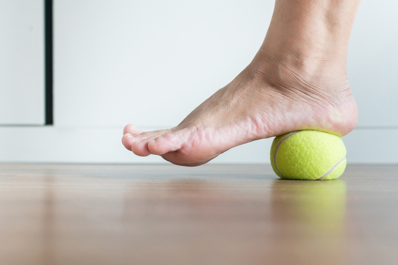 Women massaging foot with tennis ball